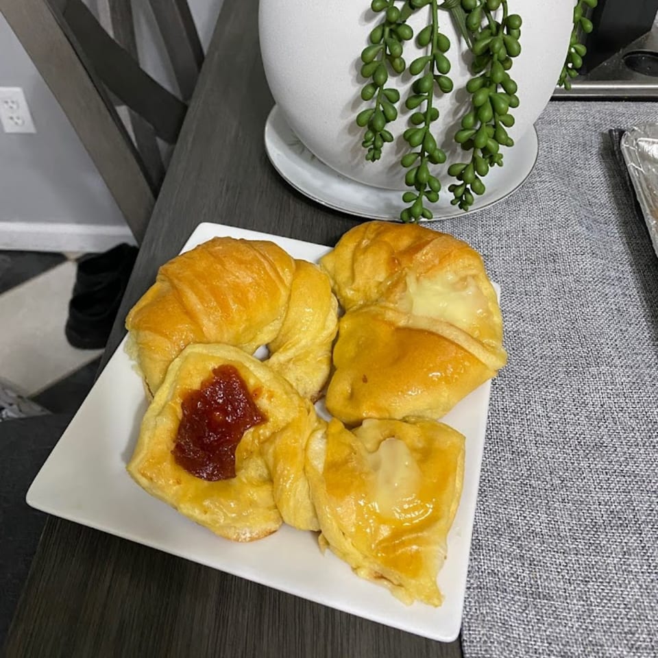 A white plate holds golden Argentinian pastries, some filled with guava paste, others with cheese.